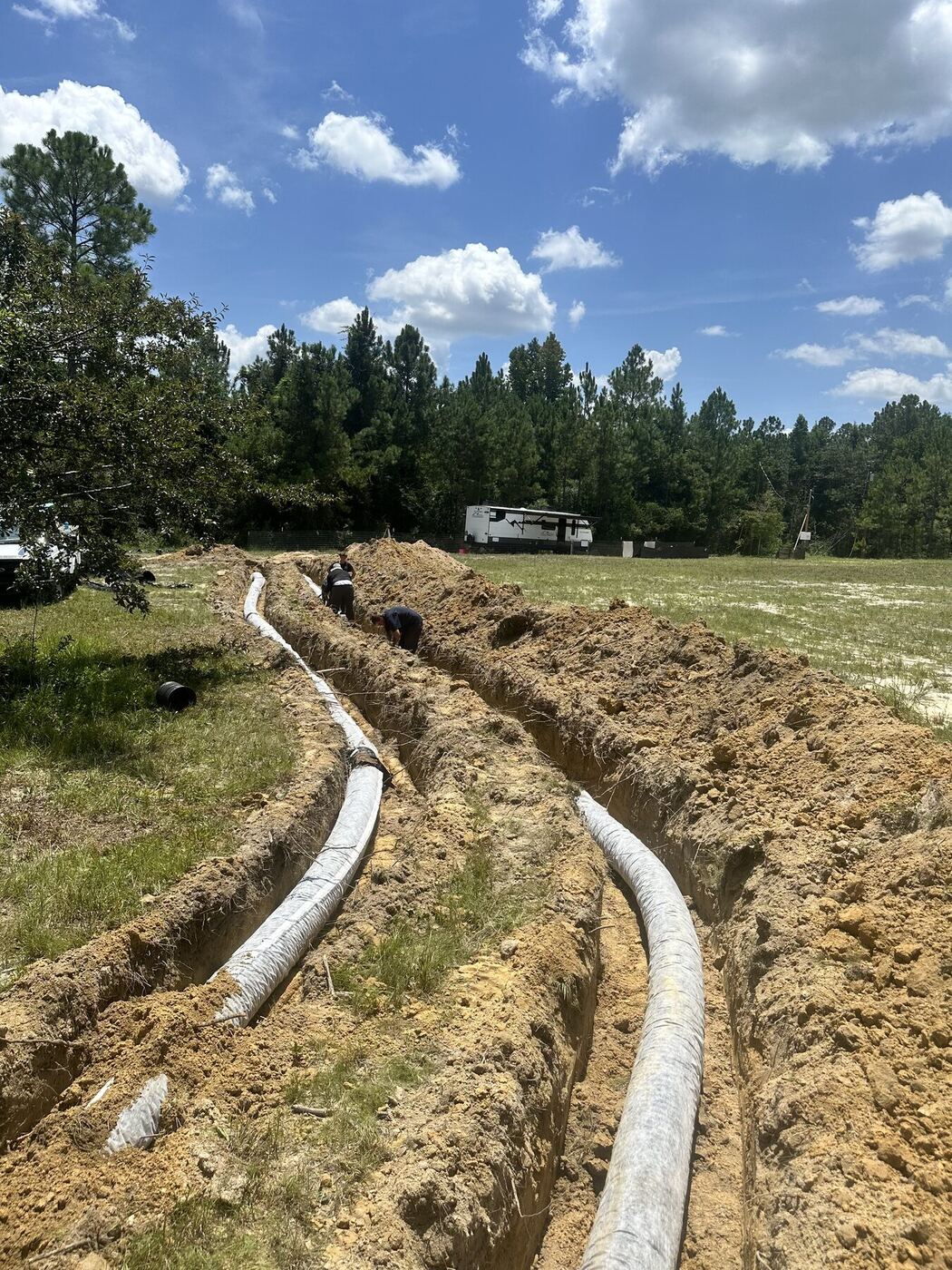 Quick Rooter crew installing septic field lines in two trenches