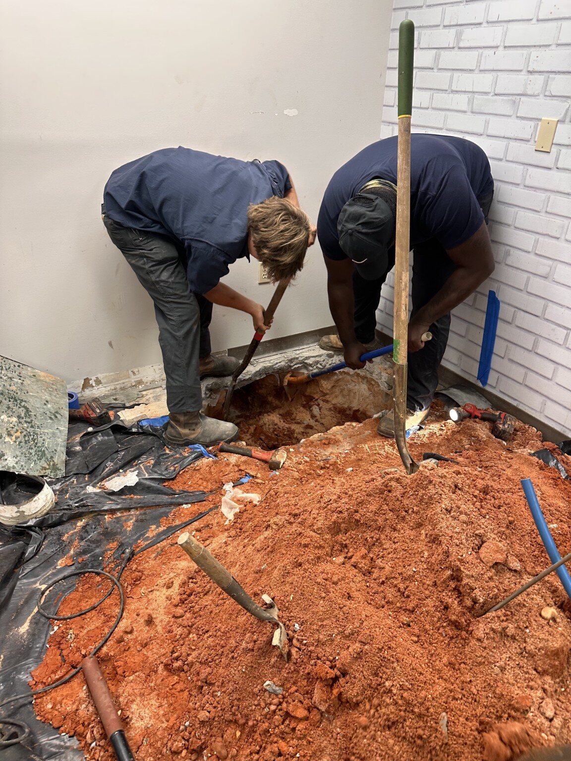Two Quick Rooter plumbers excavating an underground drain line