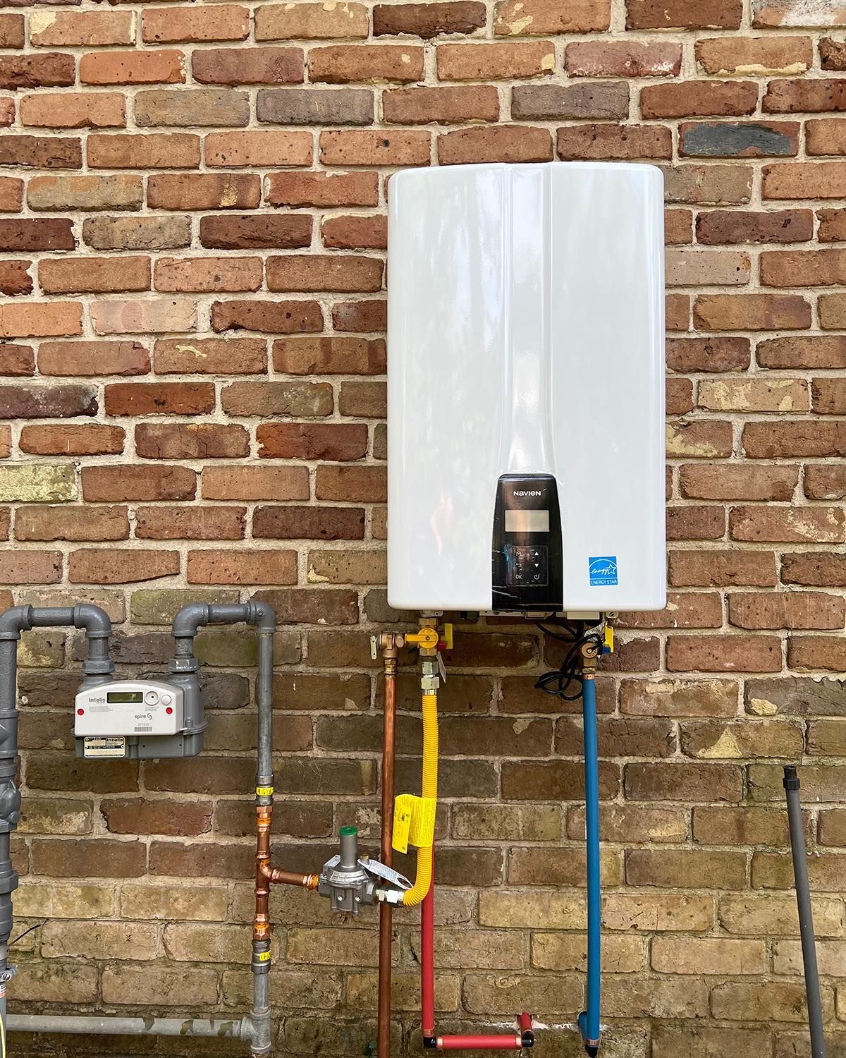 Tankless water heater installed on an exterior brick wall