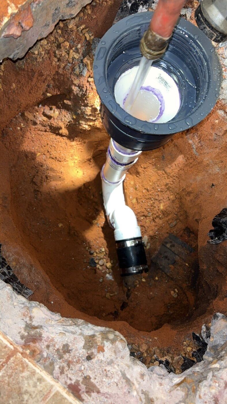 New PVC drain fitting installed below a concrete slab